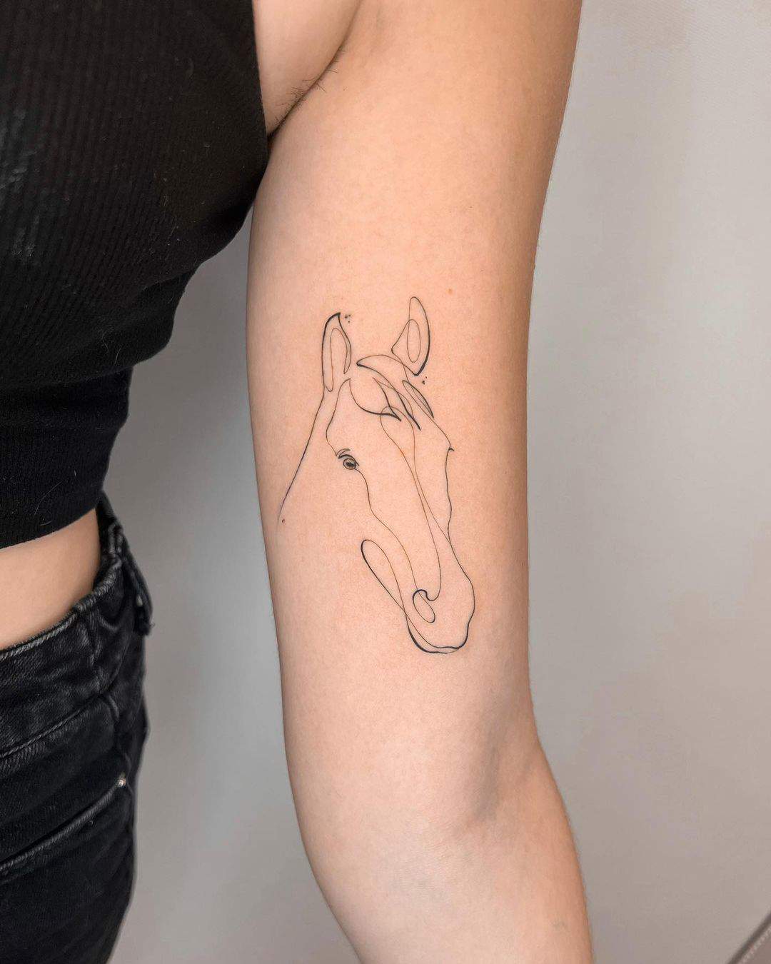 Un caballo en trazo fino tatuado en el brazo