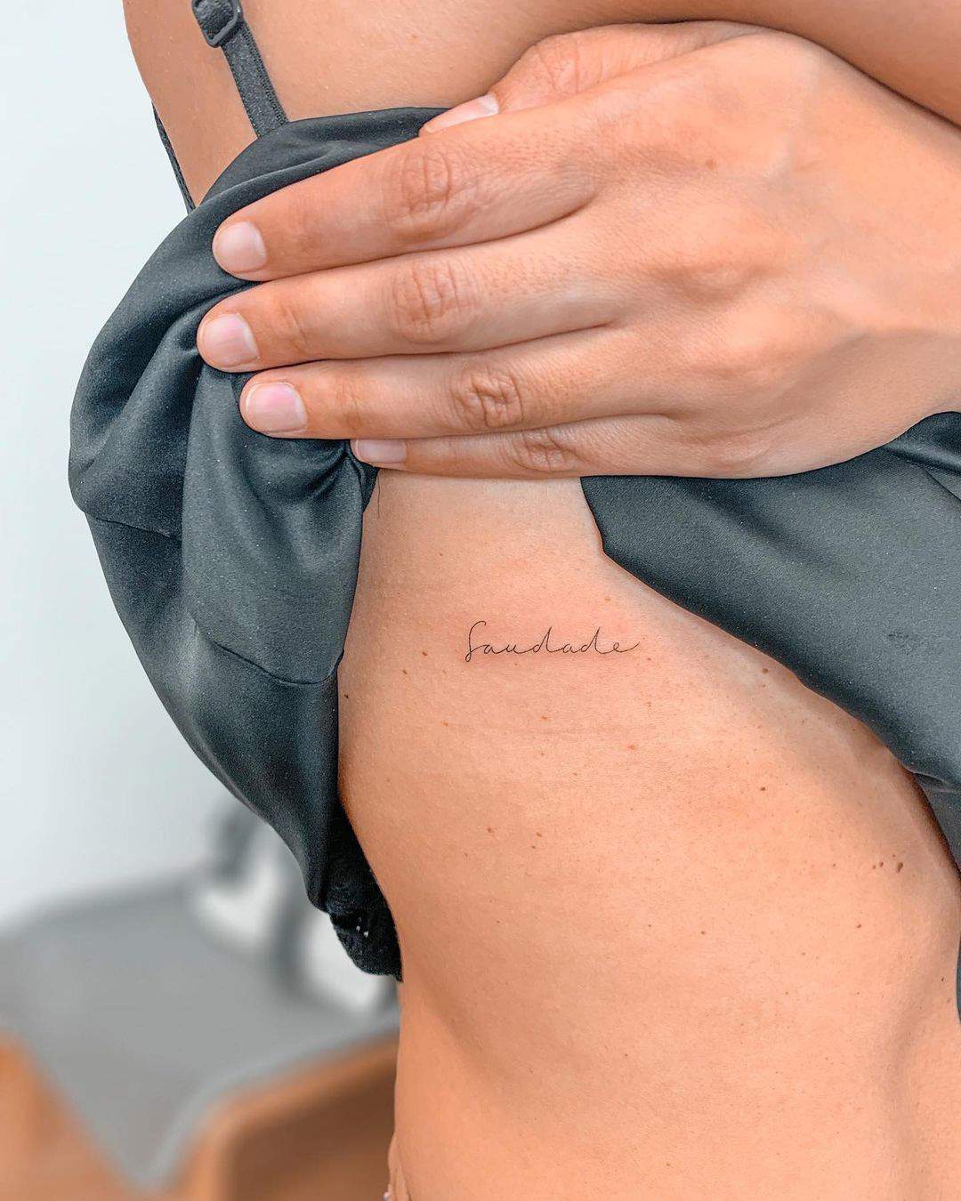 La palabra saudade tatuada en el costado