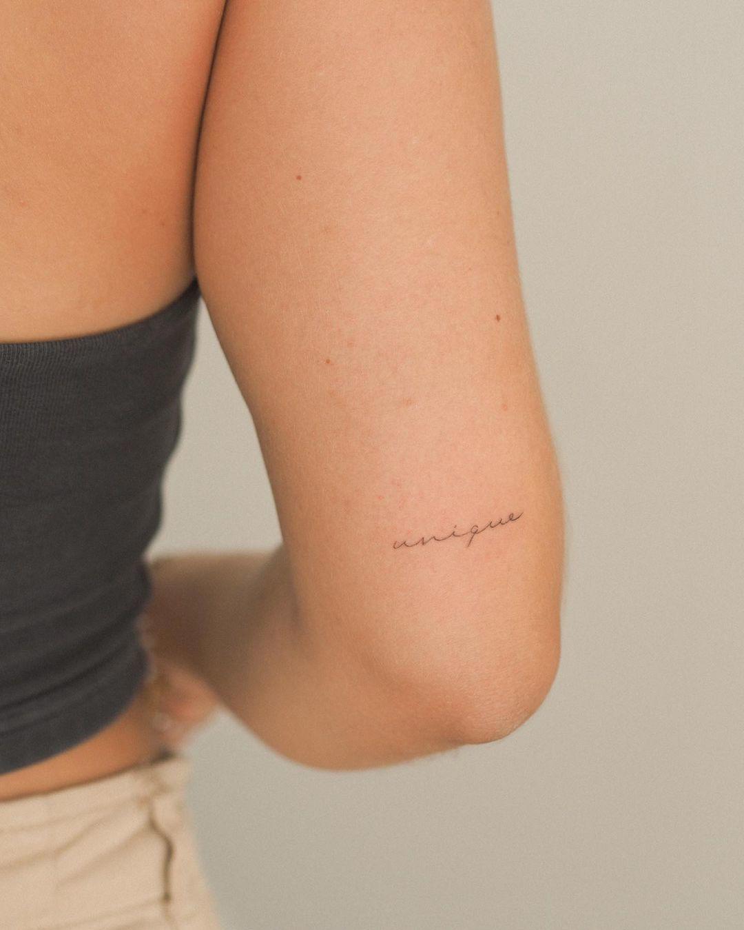 Tatuaje de palabra 'fine line' sobre el codo