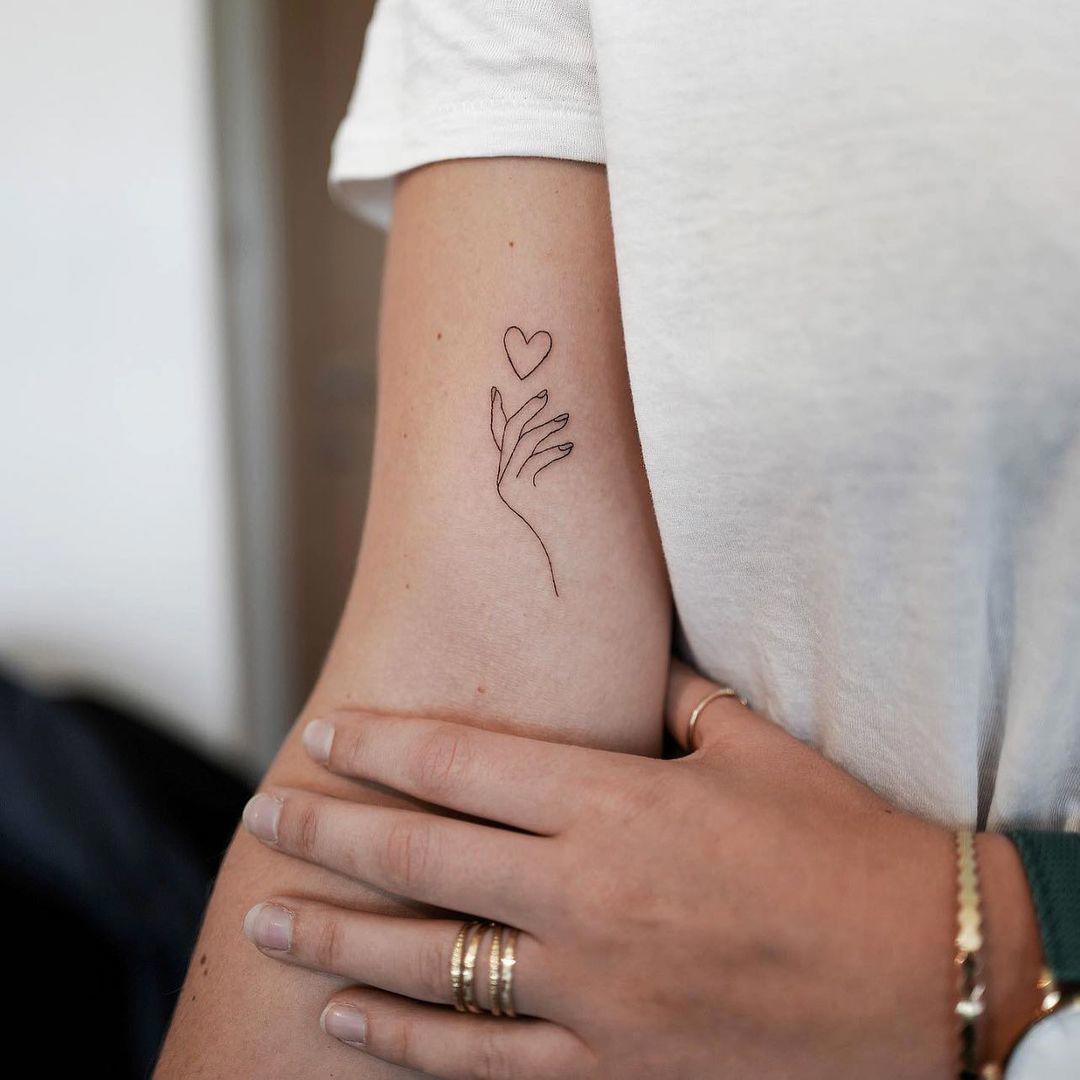Tatuaje en el brazo de un corazón y una mano