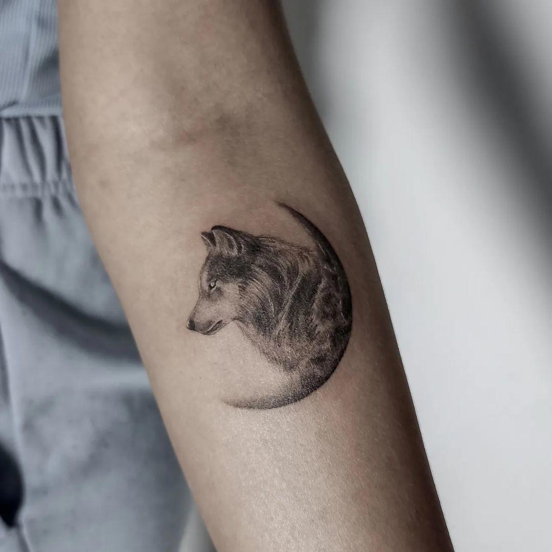 Tatuaje de lobo y luna en el antebrazo