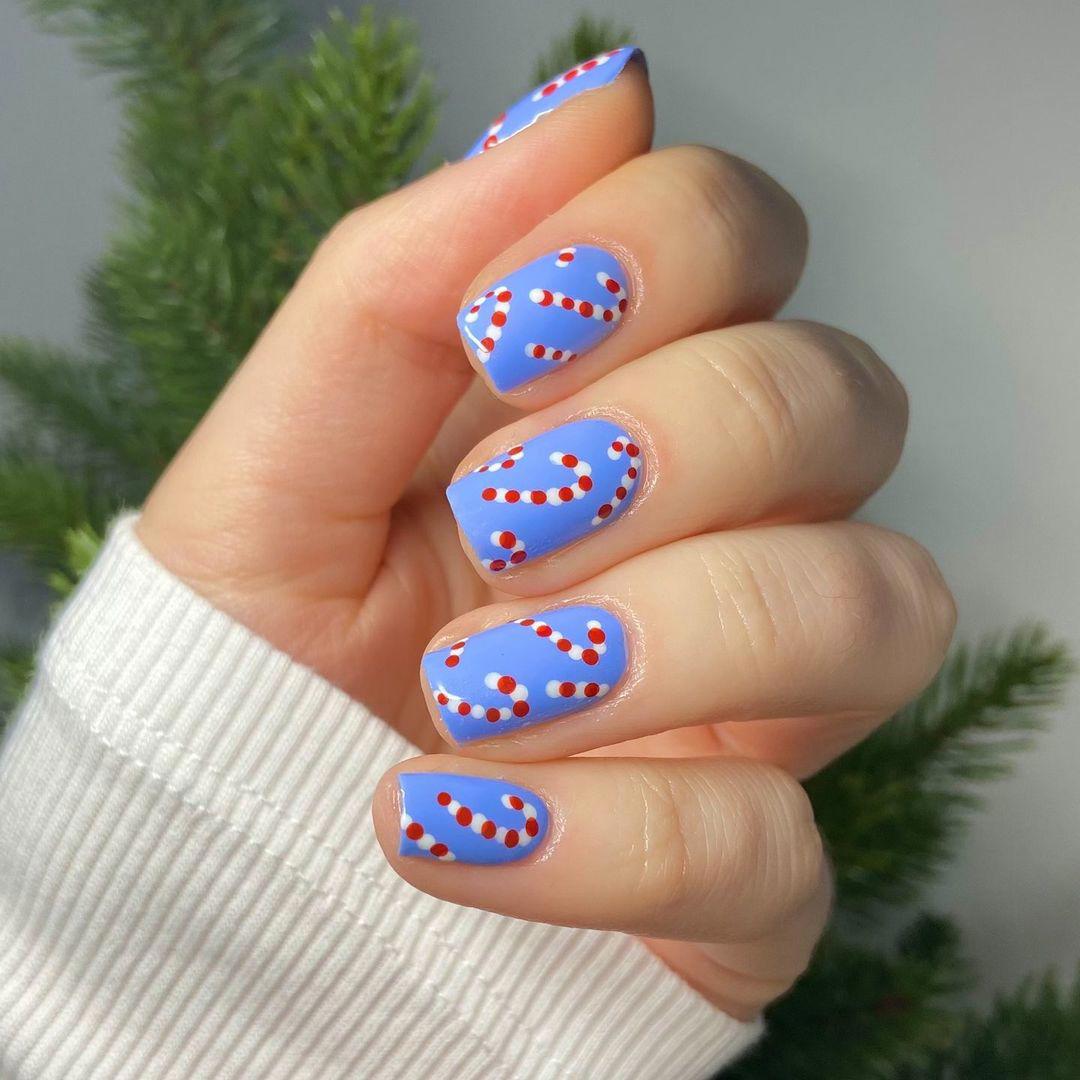 Ideas para uñas Navidad: uñas azules con bastón de caramelo
